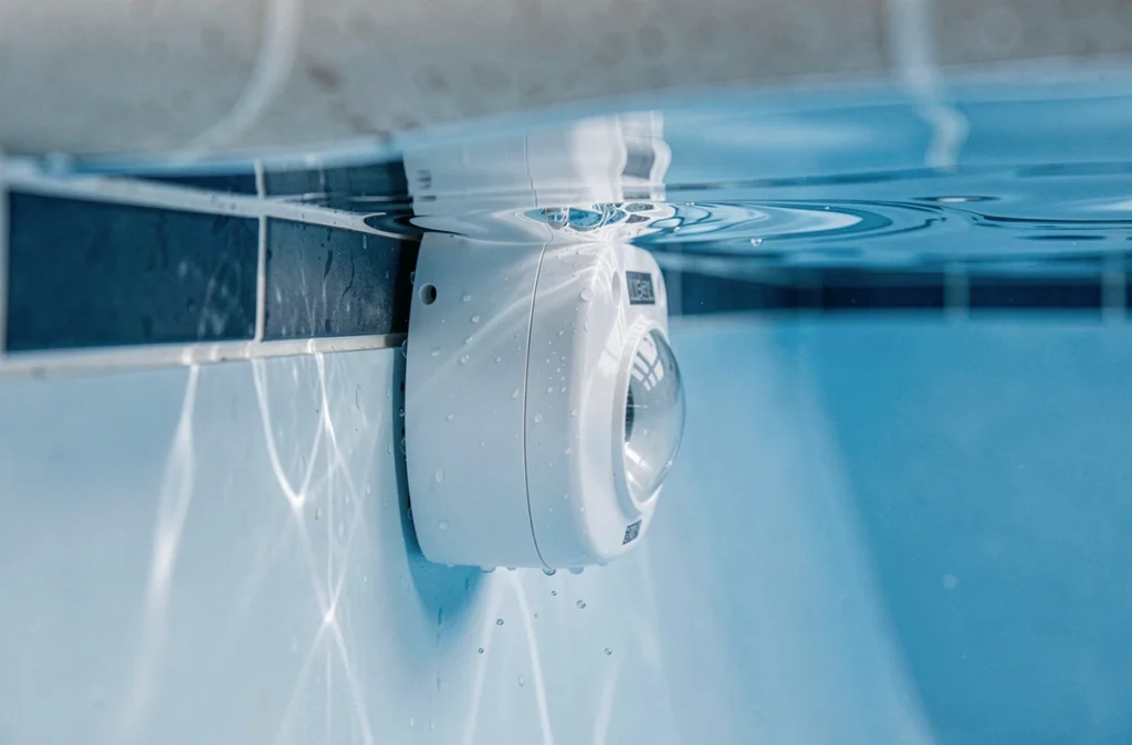 Gros plan sur un dispositif d'alarme immergée fixé à la paroi intérieure d'une piscine sous la surface de l'eau