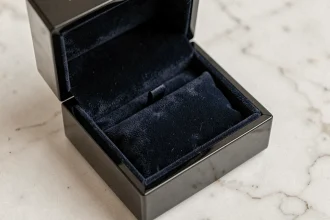 Boîte à cadeau vide pour bijoux en velours bleu marine ouverte sur un marbre blanc, style écrin de bijouterie