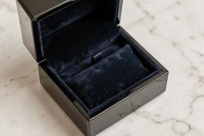 Boîte à cadeau vide pour bijoux en velours bleu marine ouverte sur un marbre blanc, style écrin de bijouterie
