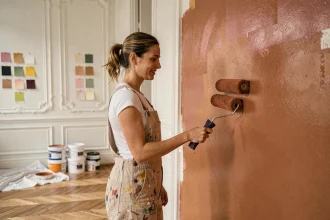Femme appliquant une peinture terracotta tendance sur un mur dans un appartement parisien avec parquet en chêne