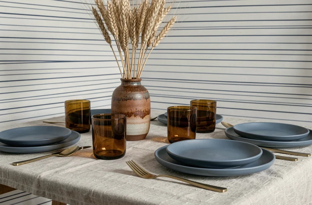 Table de salle à manger moderne dressée avec vaisselle bleue et accessoires ambrés illustrant les couleurs complémentaires au bleu