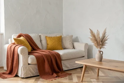 Salon minimaliste scandinave avec canapé en lin crème agrémenté d'un jeté en laine terracotta et de coussins jaune moutarde sur parquet en chêne clair