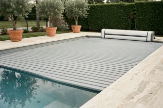 Volet roulant électrique déployé sur une piscine résidentielle moderne avec margelles en travertin